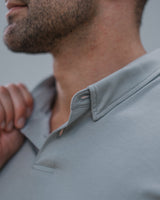 Close-up of a man wearing a light gray polo shirt, showing the collar, button, and fabric texture.